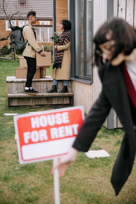 In front of a modern wooden residential building with large glass windows, two people are engaged in a conversation on a small wooden deck, with one person holding a cardboard box. Near the scene, a woman in a dark blazer is placing a bright red and white 'HOUSE FOR RENT' sign into the grass, which indicates a property available for lease. The scene is well-lit with natural daylight, and the surrounding area features a small lawn with some paving stones. This image captures aspects of property transition, emphasizing the importance of professional cleaning services offered by Cleaner Edgware to ensure properties are well-maintained before or after tenancy changes, supporting thorough surface cleaning, sanitisation, and deep cleaning for residential or commercial spaces.